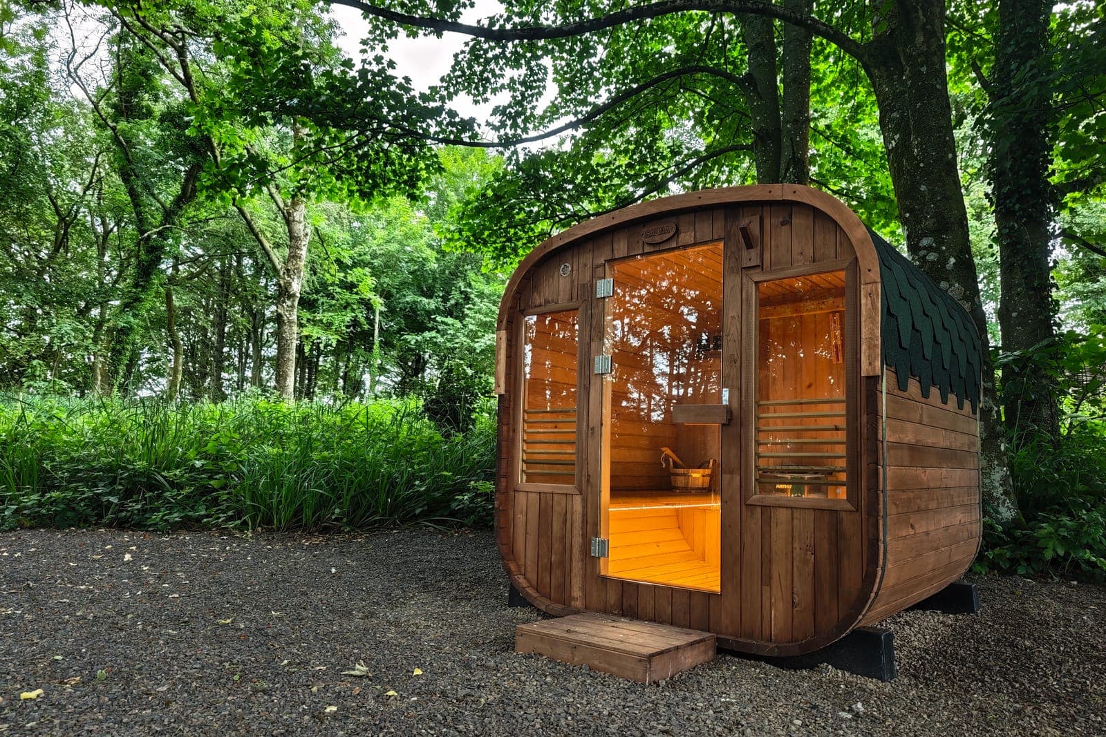 Wood-fired barrel sauna glowing warmly among the trees at Cromore Retreat
